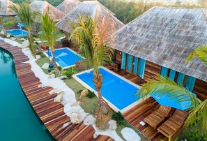 Ein Resort mit Bungalows über dem Wasser, einer Holzterrasse und einem Schwimmbad.