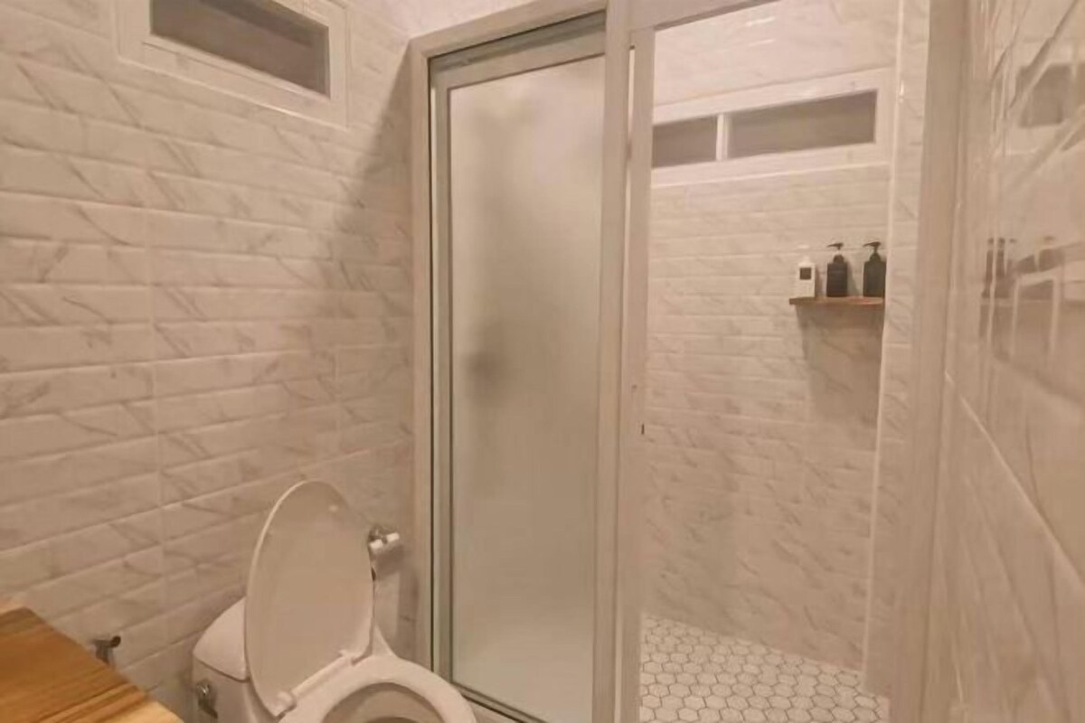 A bathroom with a toilet, a shower with a glass door, and a tiled floor.