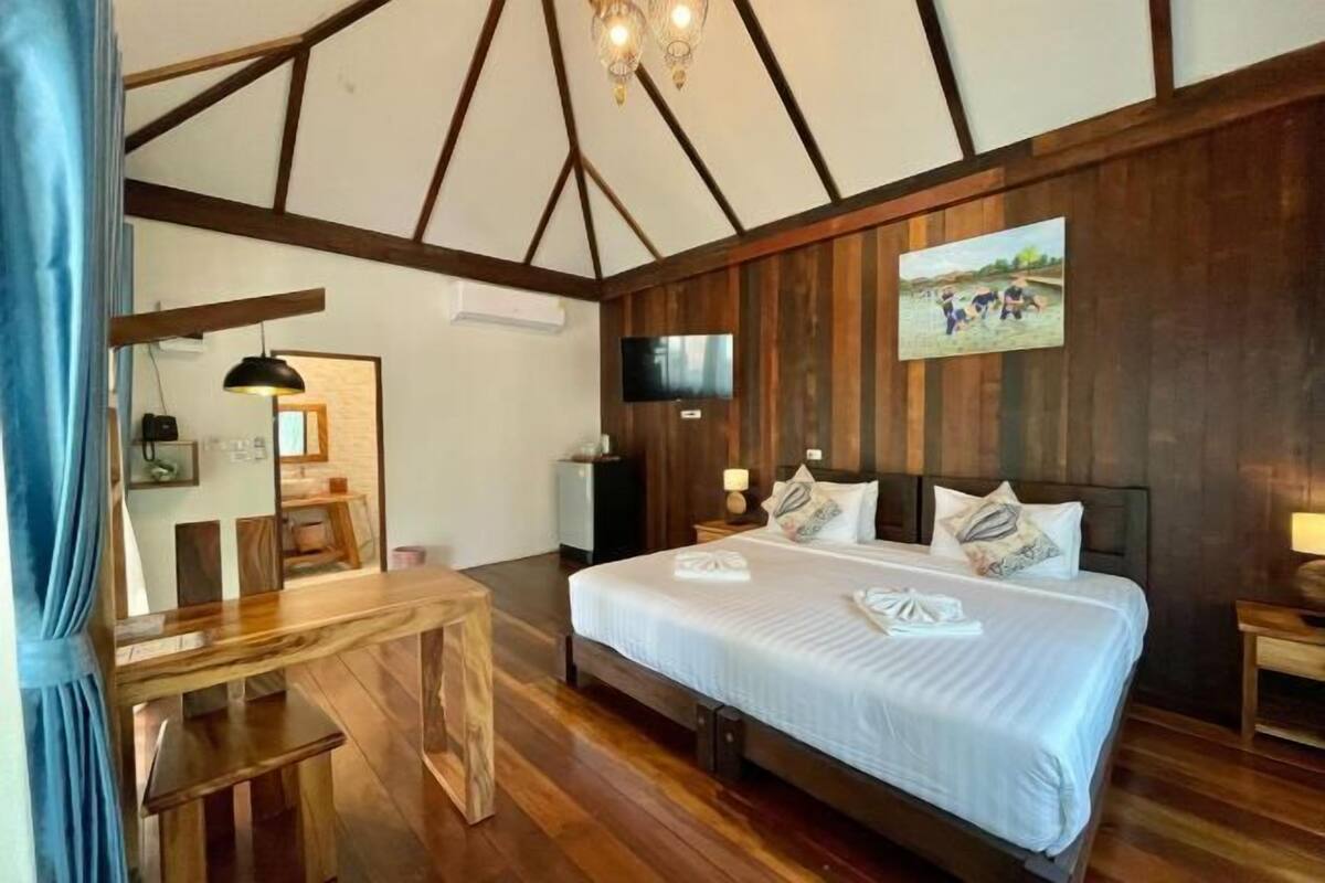 A bedroom with a wooden bed, a desk, a TV, and a painting on the wall.