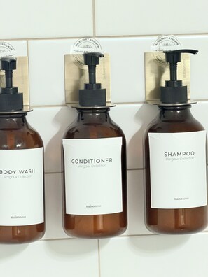 Three bottles of maisonnovo products: body wash, conditioner, and shampoo, each with a pump dispenser and a white label.