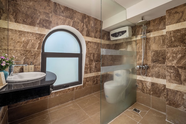 A modern bathroom with a glass-enclosed shower, a vanity with a sink, and a window with frosted glass.