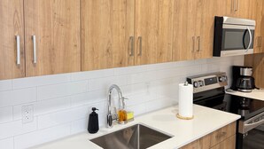 Une cuisine moderne avec des meubles en bois, des appareils en acier inoxydable et un plan de travail blanc.