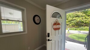 Un couloir avec une porte, une horloge murale et une pancarte de bienvenue.