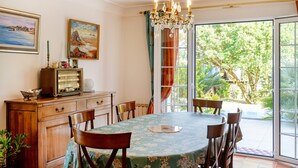 A dining area with a table, chairs, a chandelier, a radio, and a painting. - Émilie's Guest Room - Anglet (Anglet)