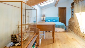 A bedroom with a skylight, wooden furniture, a bed with blue bedding, and a ship model. - Émilie's Guest Room - Anglet (Anglet)