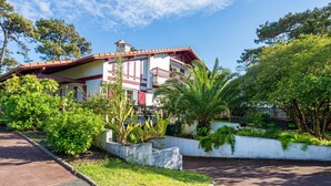A two-story building with a red roof, surrounded by lush greenery and trees. - Émilie's Guest Room - Anglet (Anglet)