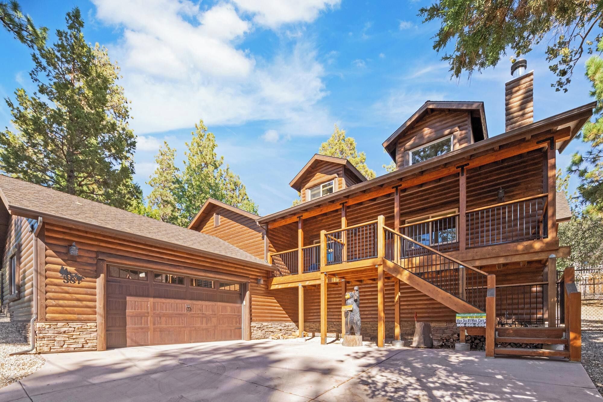 Eine Blockhütte mit Garage, überdachter Veranda und Schornstein.