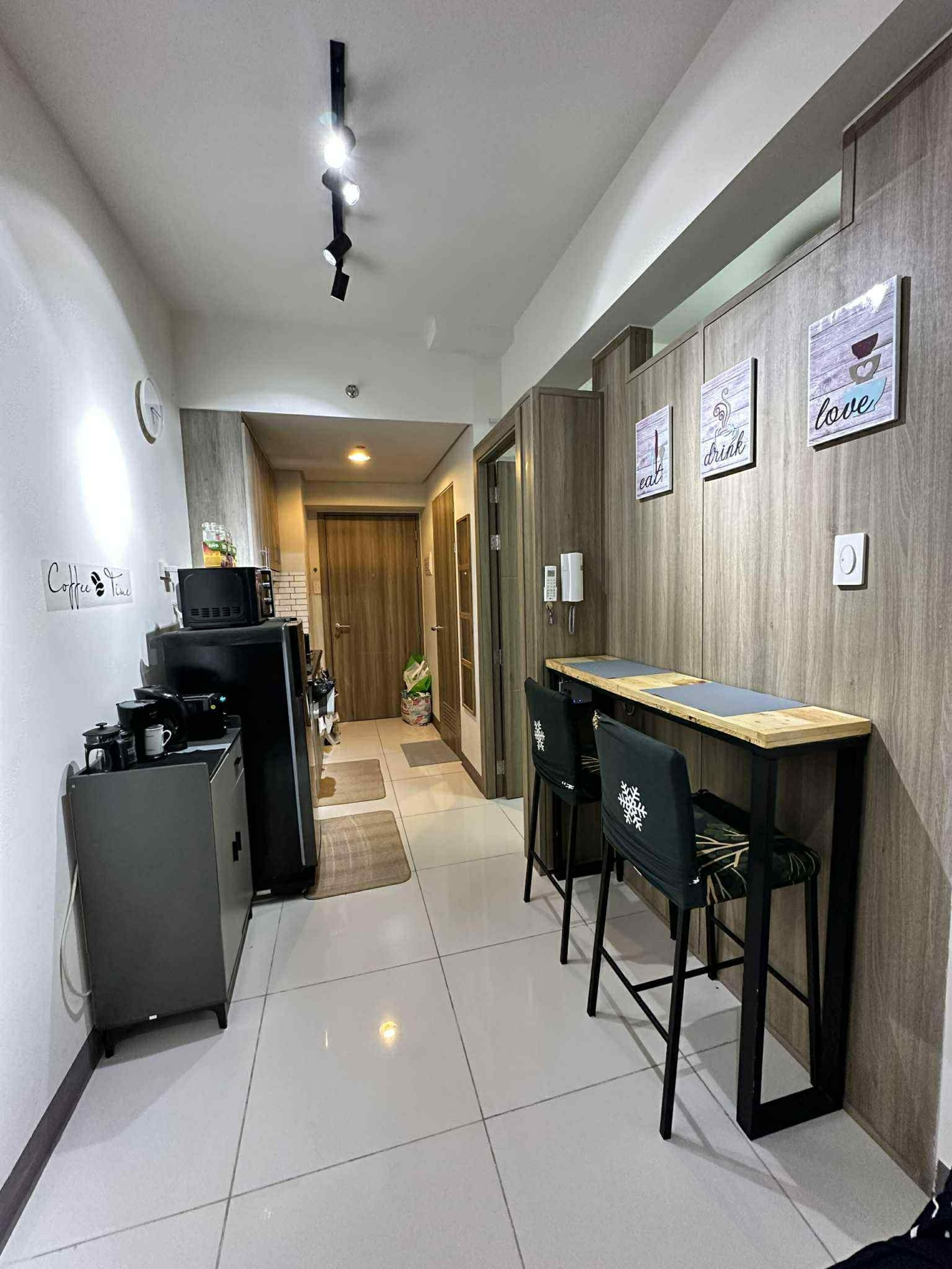 Una cocina moderna con cafetera, microondas y refrigerador. Hay una mesa de comedor de madera con sillas y una pequeña isla de cocina.