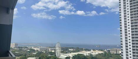 A high-rise building with a view of a Ferris wheel and a body of water in the distance.