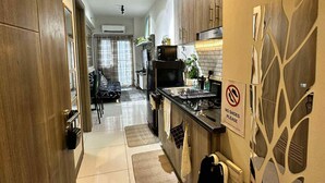 A modern kitchen with wooden cabinets, a microwave, and a sink. There is a 'No Shoes Please' sign on the wall. - Modern Comfort in Pasay with Pool (Pasay)