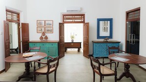 Un comedor con dos mesas y sillas de madera, un armario azul y un aparador de madera con detalles decorativos.