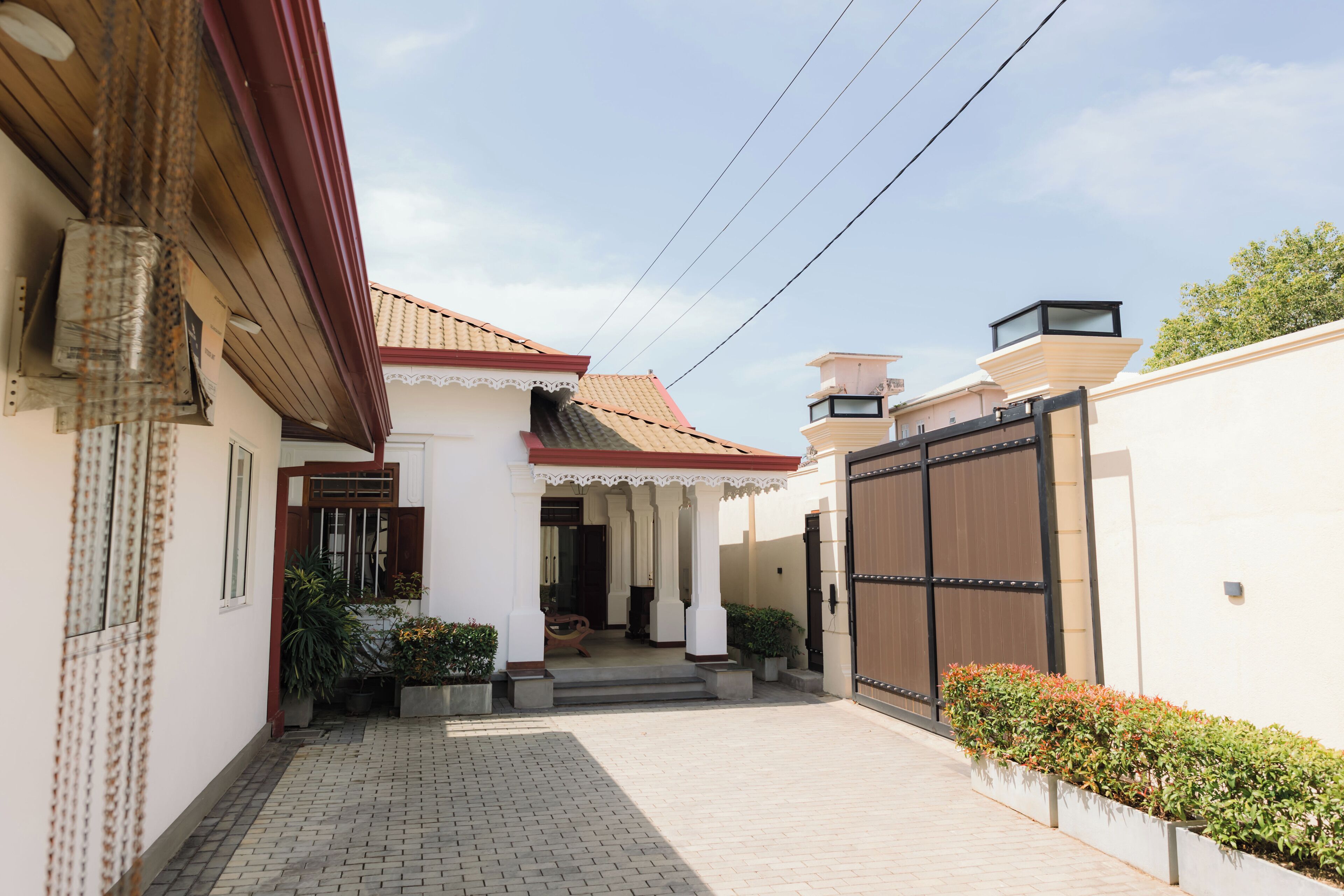 A narrow, paved pathway leading to a building with a tiled roof and a large black gate.
