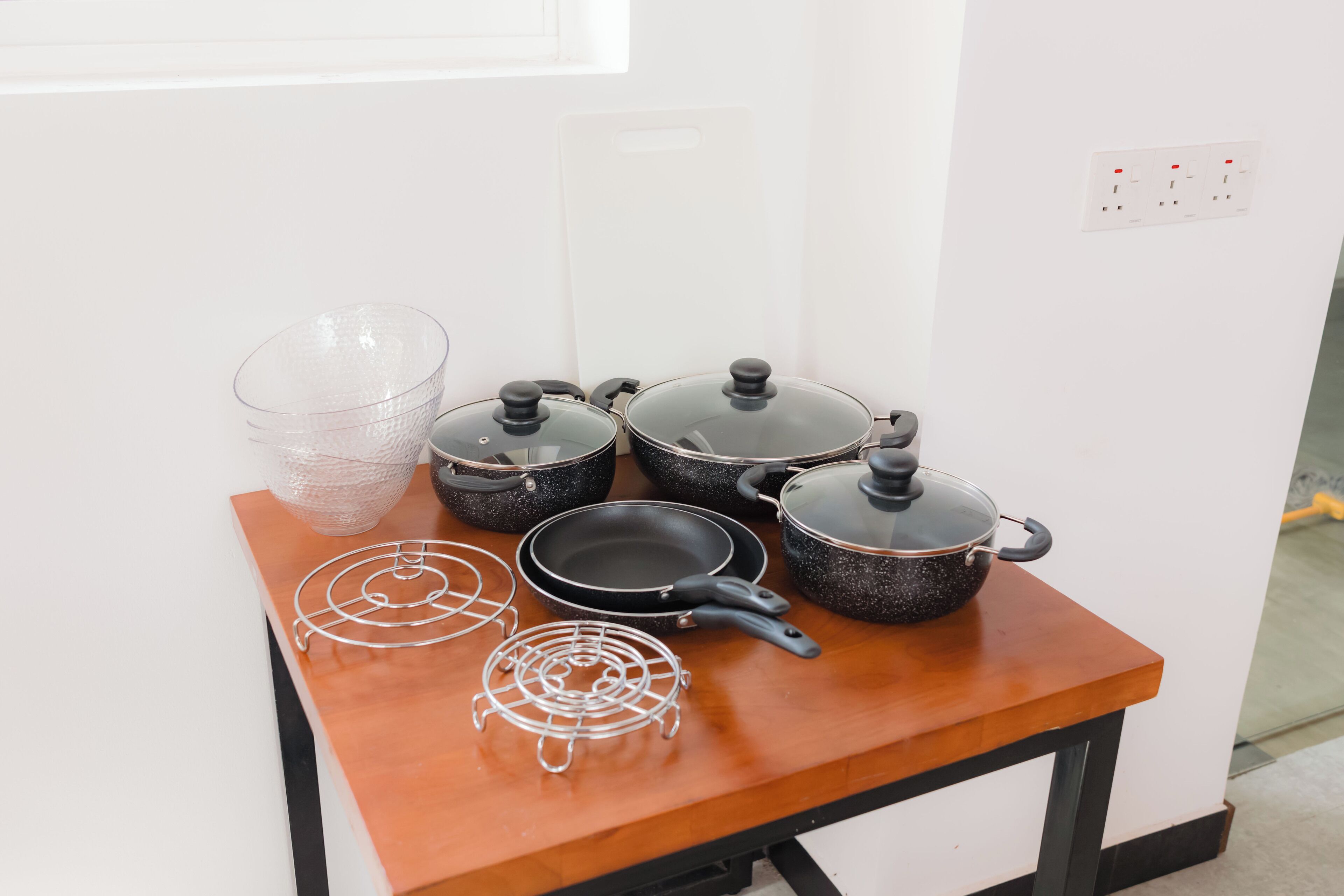 A kitchen counter with various cookware including pots, pans, and a wire rack.