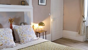 Una camera da letto con un letto, un comodino con una lampada, una porta e una finestra con tende.