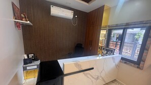 A reception area with a marble counter, a wooden slatted wall, and a window with decorative patterns. - MSK Homestay Service Apartment (Hubli)