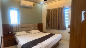 A bedroom with a bed, nightstand, and an air conditioning unit. - MSK Homestay Service Apartment (Hubli)
