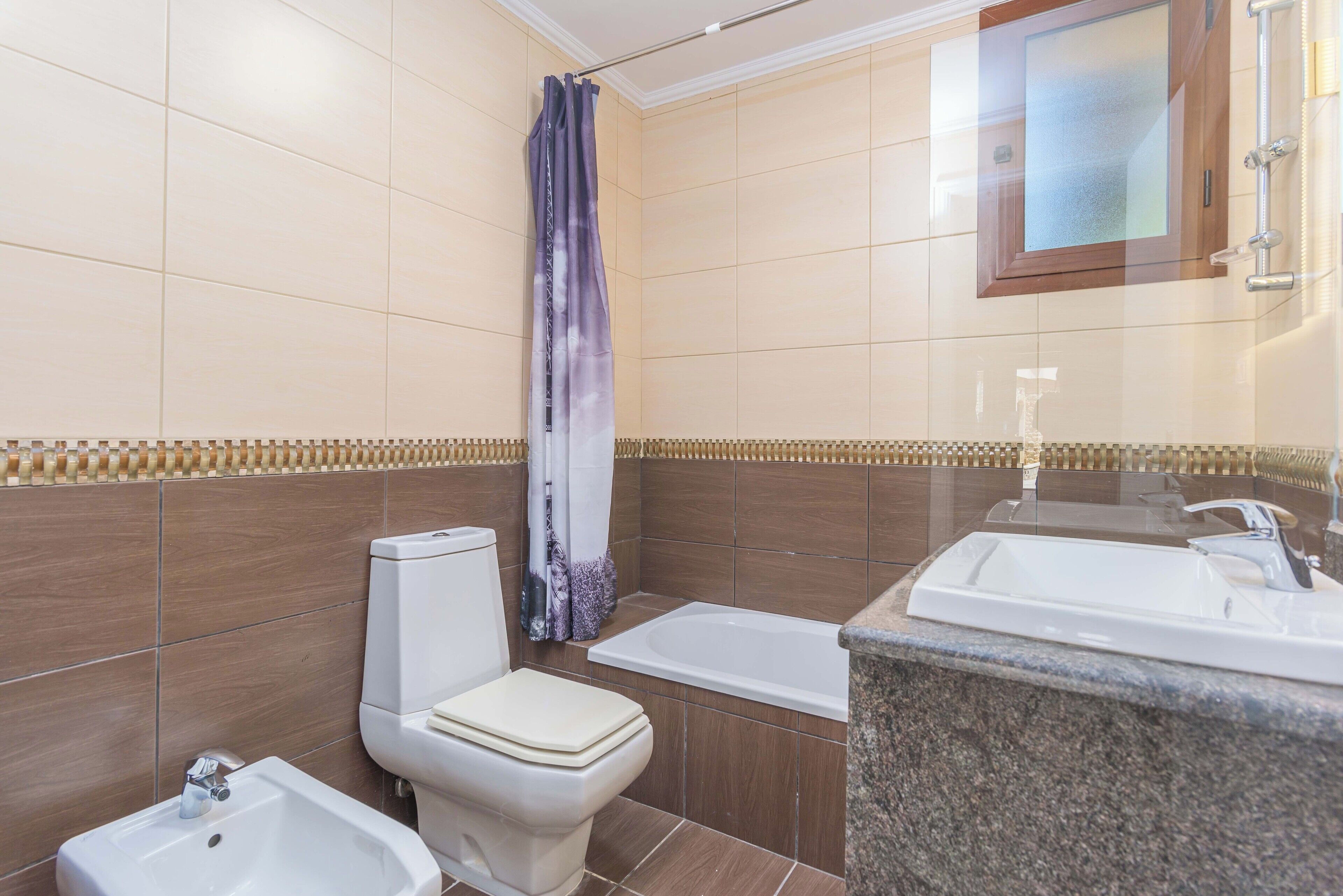 A bathroom with a toilet, bidet, bathtub, and a sink.