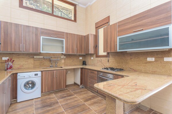 Une cuisine moderne avec des meubles en bois, un lave-linge encastré et une grande fenêtre.
