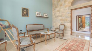 A room with a stone wall, a sofa, a coffee table, and a chair. - Beit Salima 3BR House with Pool (Salima)