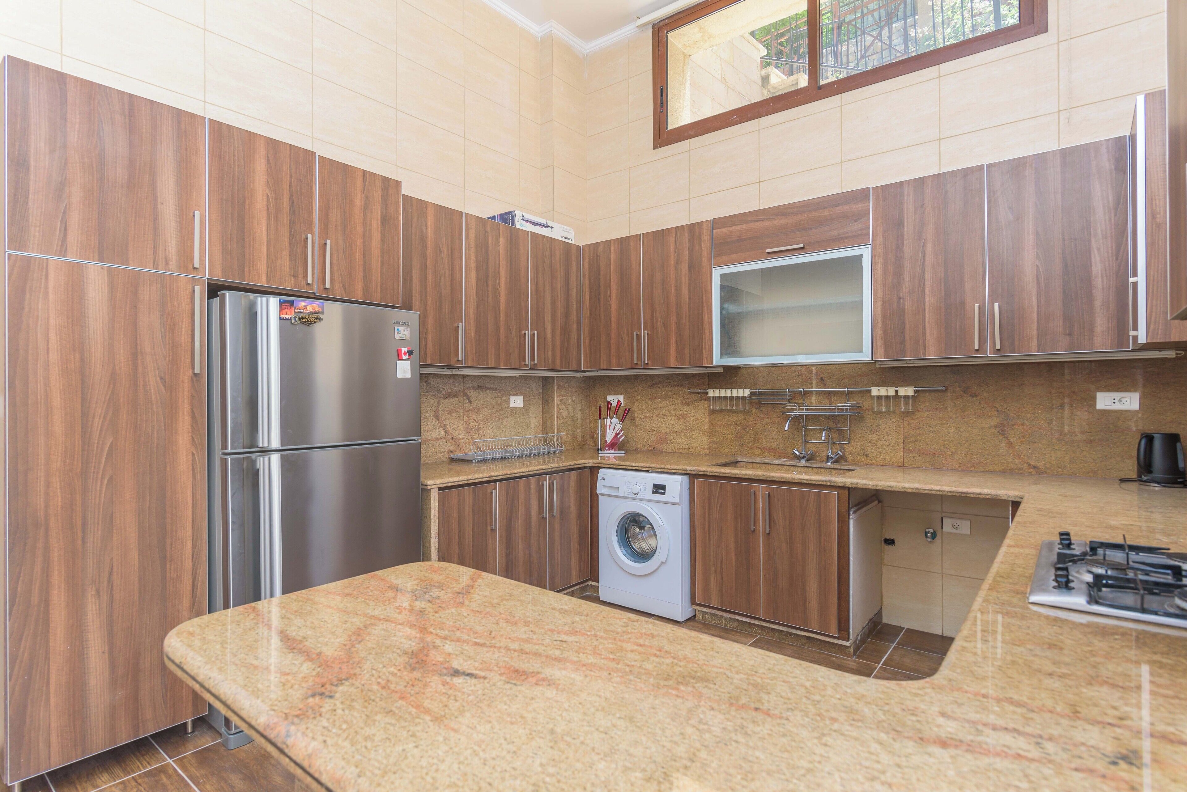Une cuisine moderne avec des meubles en bois, des appareils électroménagers en acier inoxydable, un four encastré et un plan de travail en granit.