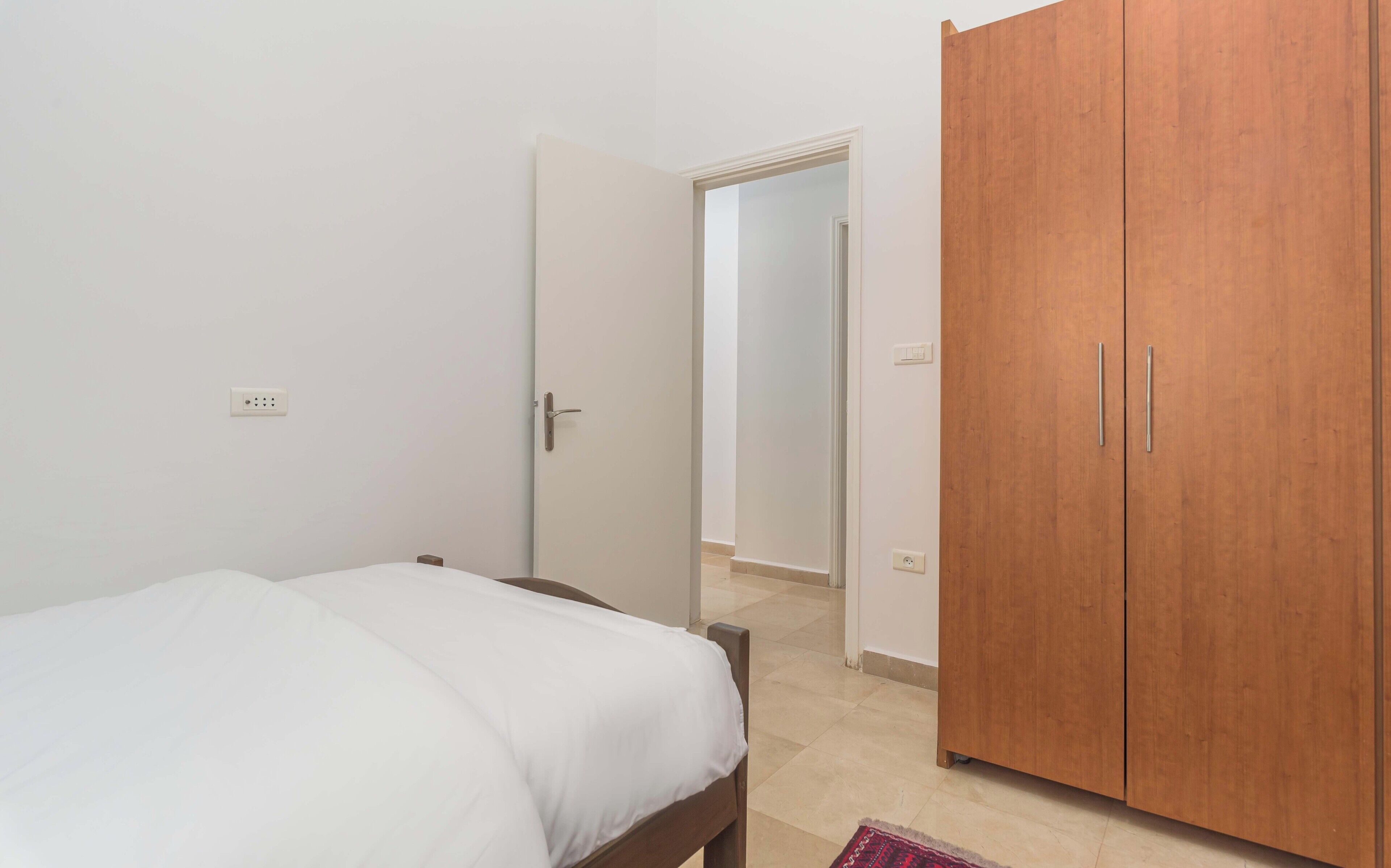 Une chambre à coucher comprenant un lit, une armoire et une porte donnant sur une autre pièce.