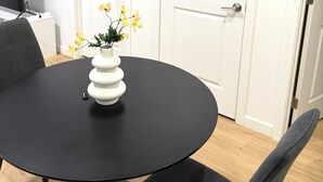 Une pièce avec une table ronde noire, un vase avec des fleurs, une chaise grise et des portes blanches.
