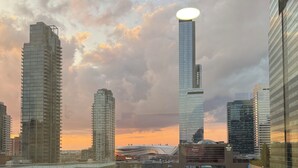 Un paysage urbain moderne, avec de hauts immeubles et une tour remarquable surmontée d’une structure circulaire.