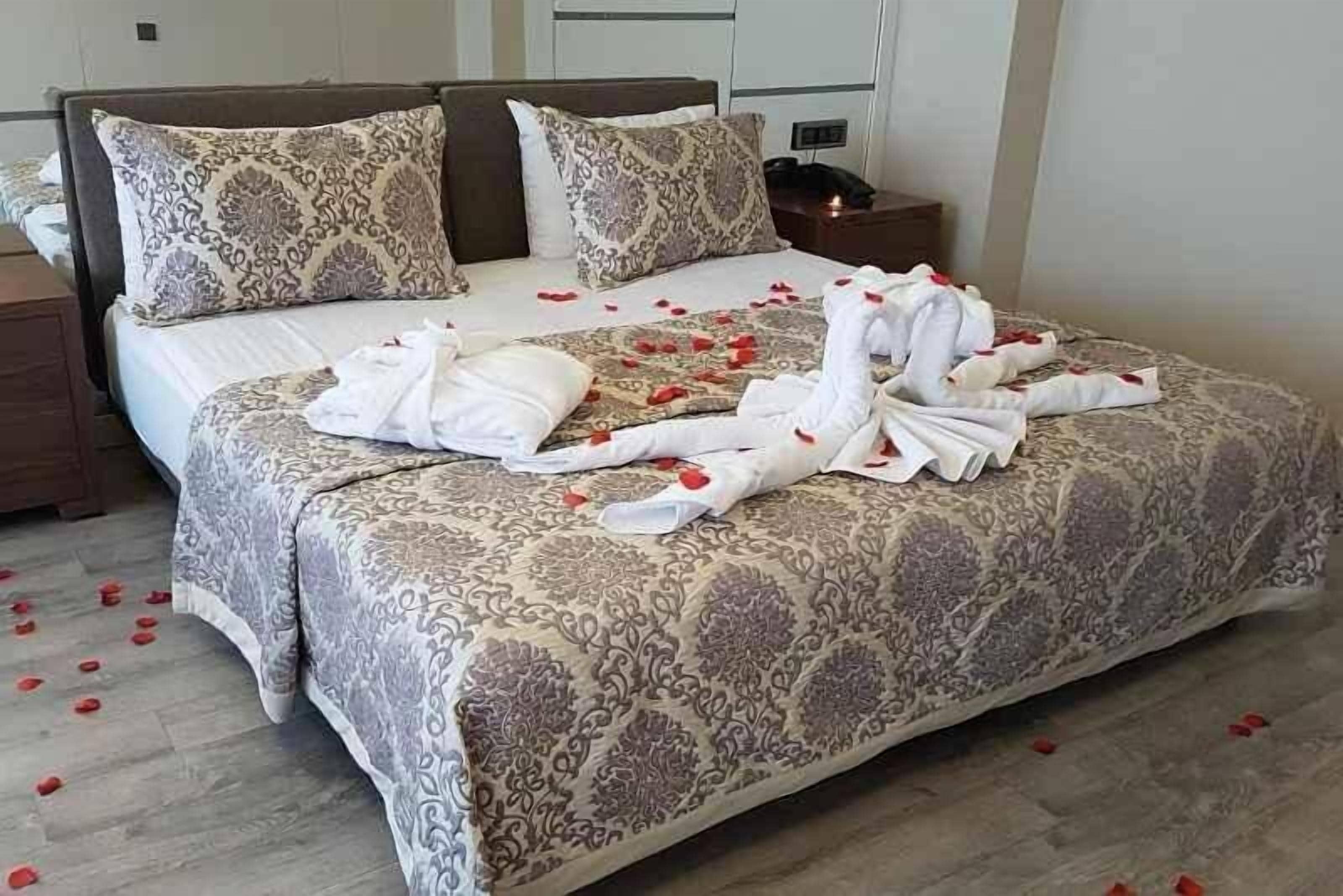 Una habitación de hotel con una cama grande, dos mesitas de noche y una mesita con lámpara.