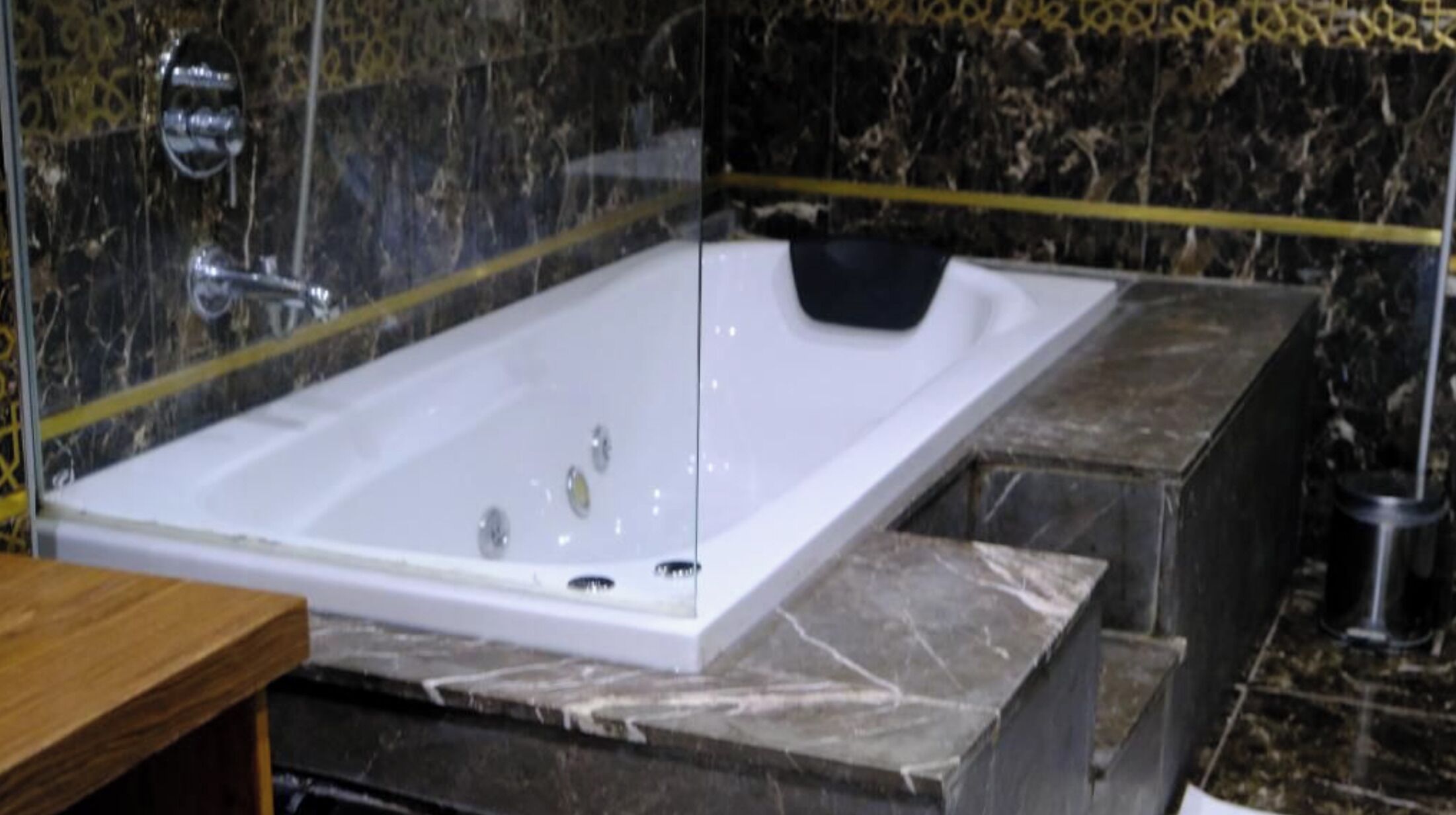 Ein modernes Badezimmer mit einer großen weißen Badewanne, Marmorplatten und einer Duschkabine aus Glas.