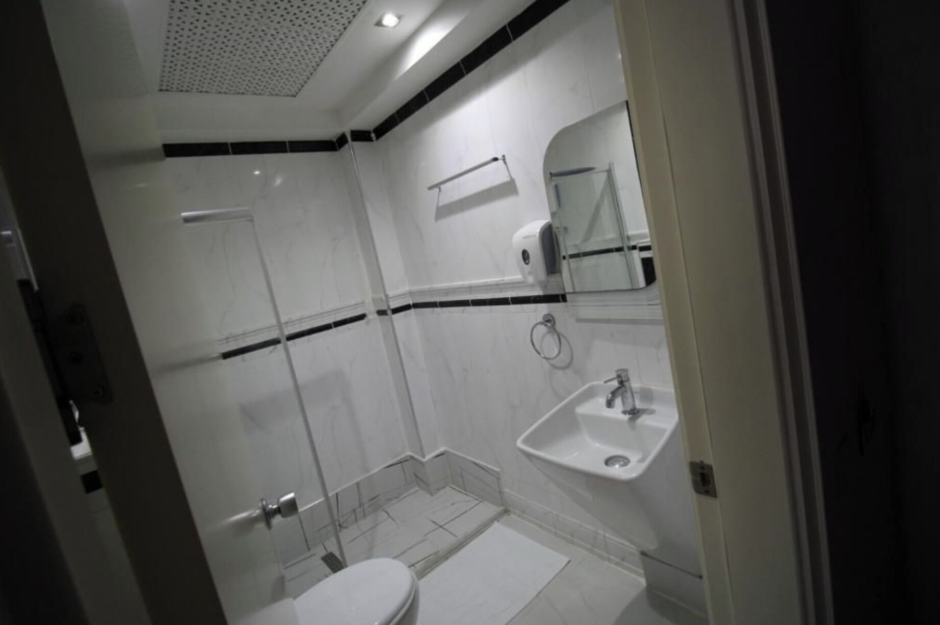 A modern bathroom with a glass shower enclosure, a toilet, and a sink.