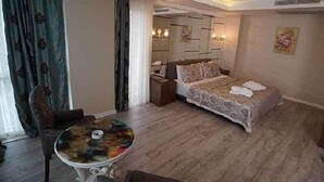 A hotel room with a bed, a round table, a chair, and a nightstand. - Atakum Palas Otel (Atakum)