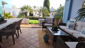 Un patio con mesa de comedor, sillas, un sofá y una mesa baja.