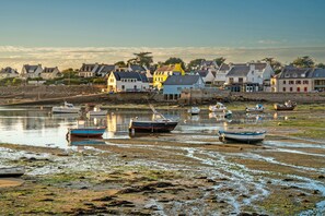 A coastal village with boats on the shore, houses in the background, and a clear sky.
