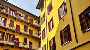 Un immeuble jaune à plusieurs étages, doté de volets rouges et de balcons.