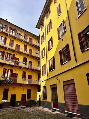 A yellow multi-story building with red shutters and balconies.