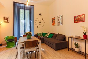 A living room with a dining table, sofa, and a clock on the wall.