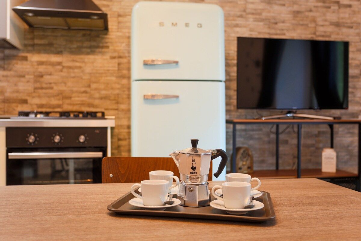 A kitchenette with a vintage-style refrigerator, a coffee maker, and a tray with cups.
