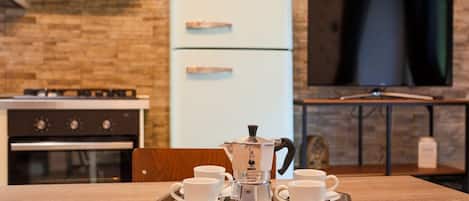 A kitchenette with a vintage-style refrigerator, a coffee maker, and a tray with cups.