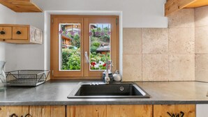 Cozinha com pia dupla, armários de madeira e vista para um jardim através de uma porta.