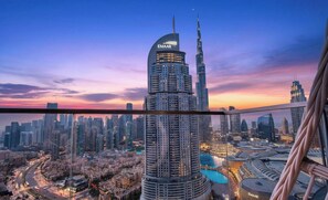 A high-rise building with a curved facade and the 'EMAAR' logo, surrounded by a dense urban skyline. - WYZ RENT|Prestigious 3.5 BR in Boulevard (Dubai)