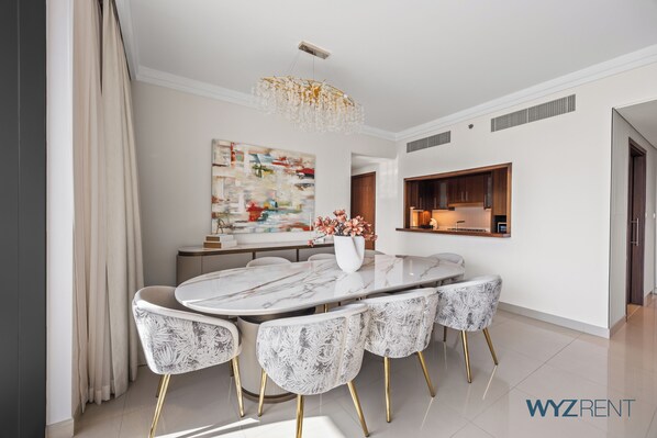 A modern dining area with a marble table, patterned chairs, a chandelier, and a large abstract painting. - WYZ RENT|Prestigious 3.5 BR in Boulevard (Dubai)