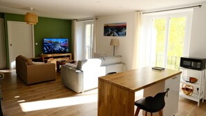 Ett modernt vardagsrum med en soffa, ett matbord, en tv och en tavla på väggen.