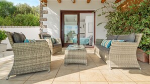 A patio with wicker furniture, a glass-top table, and a view of the interior through a glass door. - Apartment 'Sarda Bella Private Pool' with Mountain View, Wi-Fi and Air Conditioning (Rudalza)