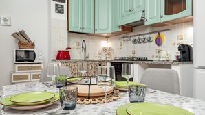 A dining area with a table set for four, a microwave, a red kettle, and a coffee maker. - Apartment 'Sarda Bella Private Pool' with Mountain View, Wi-Fi and Air Conditioning (Rudalza)