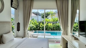 Een moderne hotelkamer met een groot bed, een televisie, een bureau en uitzicht op een zwembad en groen buiten.