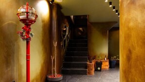 A hallway with a red decorative pole, a staircase, and potted plants. - Thea Hotel  (Prizren)