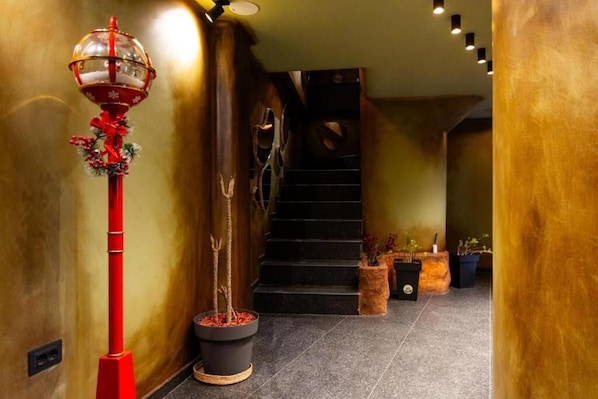 A hallway with a red decorative pole, a staircase, and potted plants.