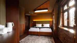 A hotel room with a wooden bed, a bedside table with a white pitcher, and a large window with a view. - Thea Hotel  (Prizren)