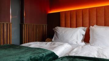 Una habitación de hotel con una cama, cabecero de madera y una pared de acento roja.