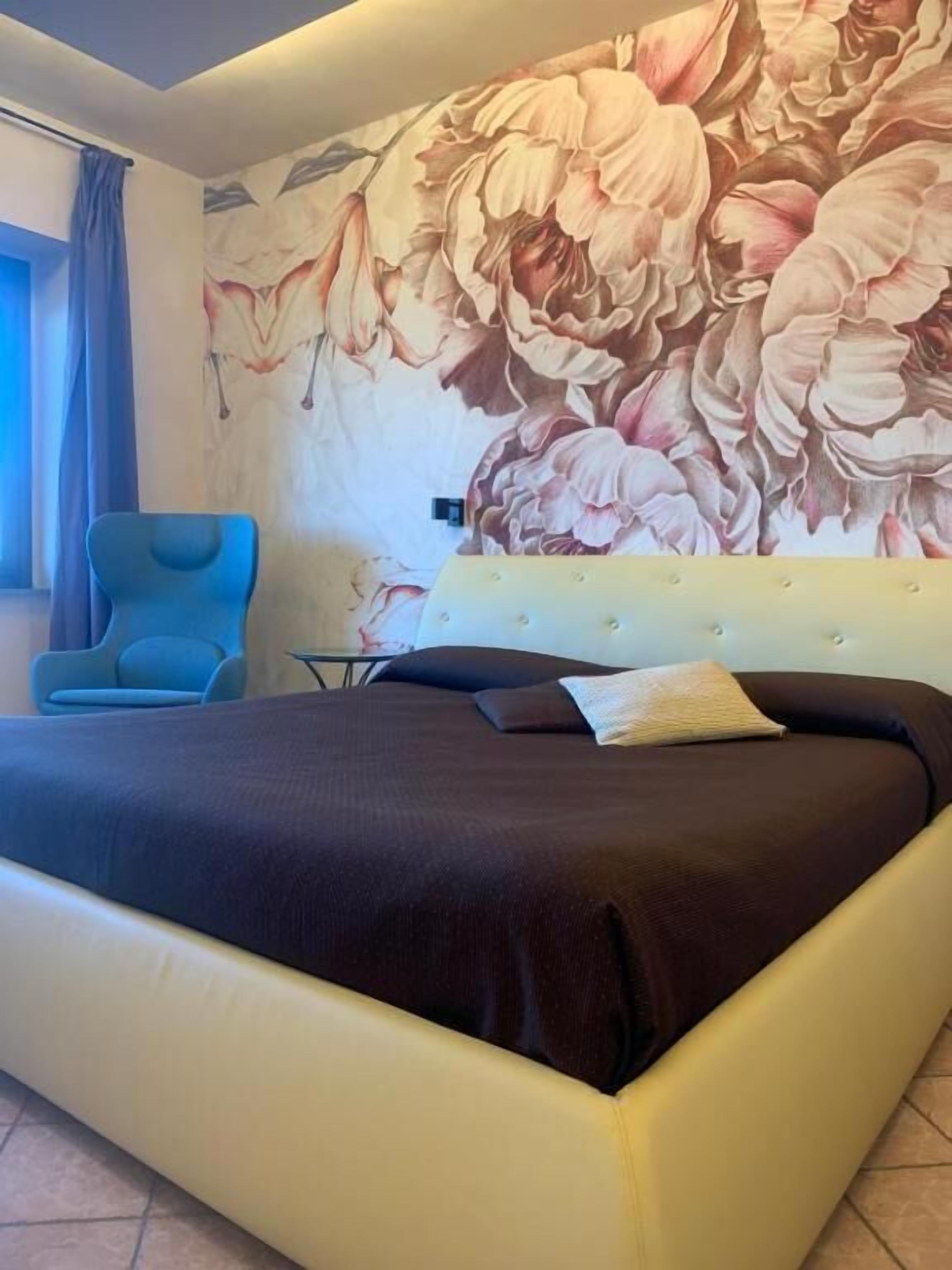 Une chambre à coucher avec un lit, une chaise et une décoration murale à motifs floraux.
